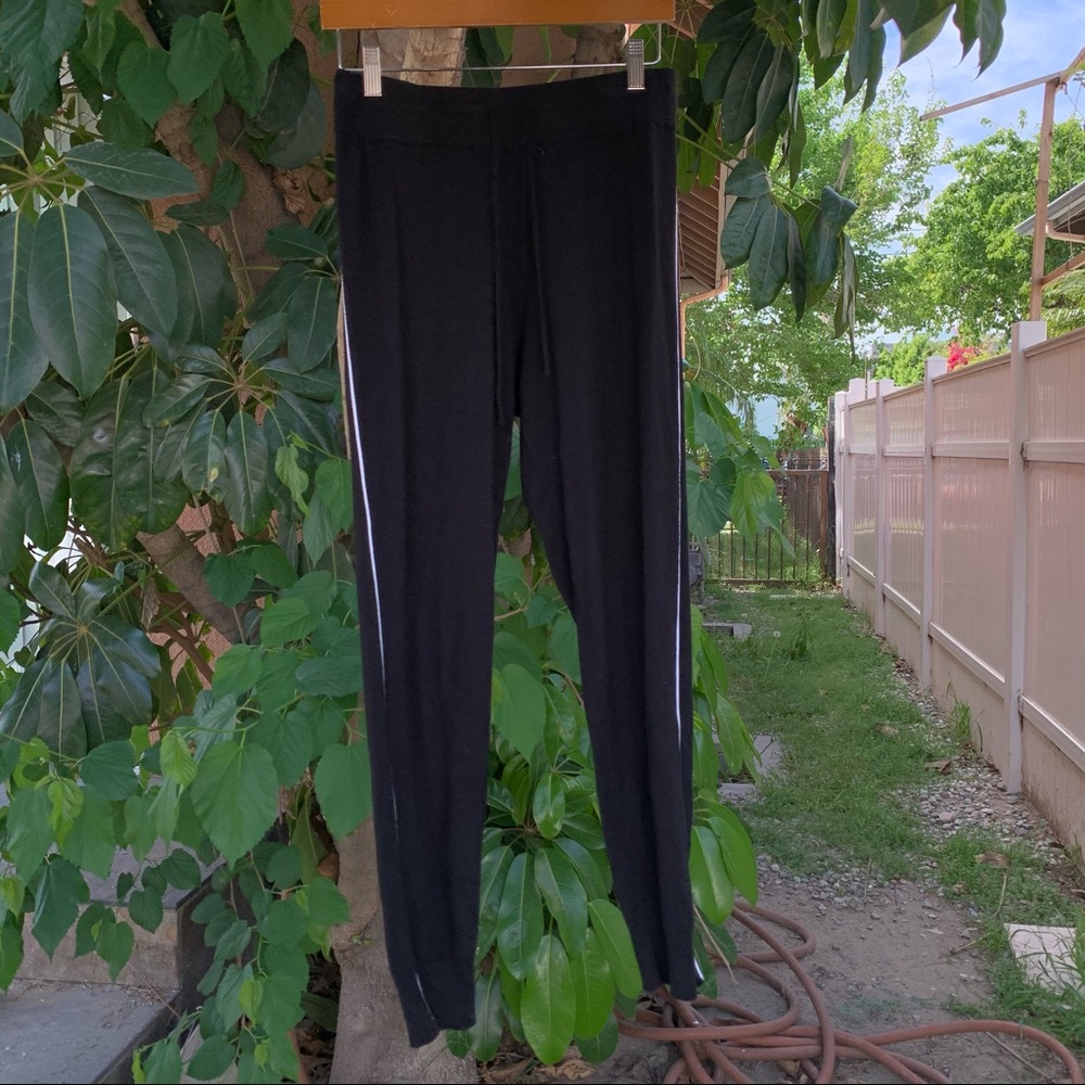 Comune black lounging pants with a white stripe on the sides.